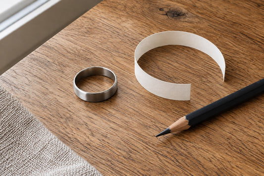 A silver ring, paper strip and pencil on a warm oak table